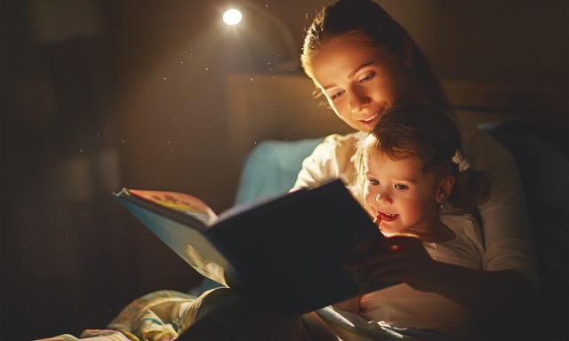 mother and child girl reading a book in bed