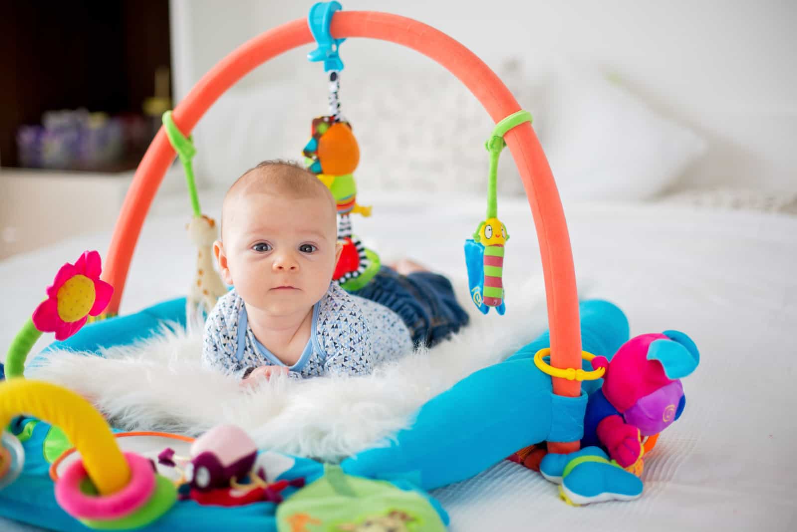 Canva-Cute-baby-boy-on-colorful-gym-playing-with-hanging-toys-at-home