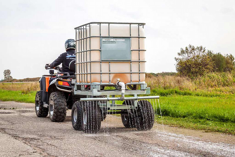 Man on ATV watering with water trailer