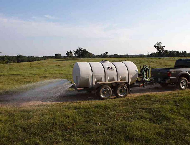 Man watering the ground with water trailer 