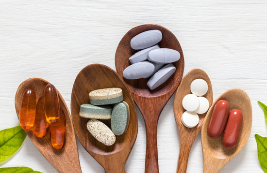 Diferent types of multivitamins in wooden spoon