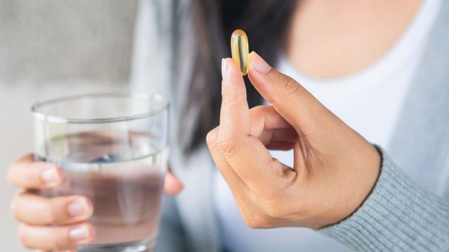 woman-holding-pill-supplement-glass-water