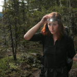 Red hair woman wearing headlamp while hiking in the woods