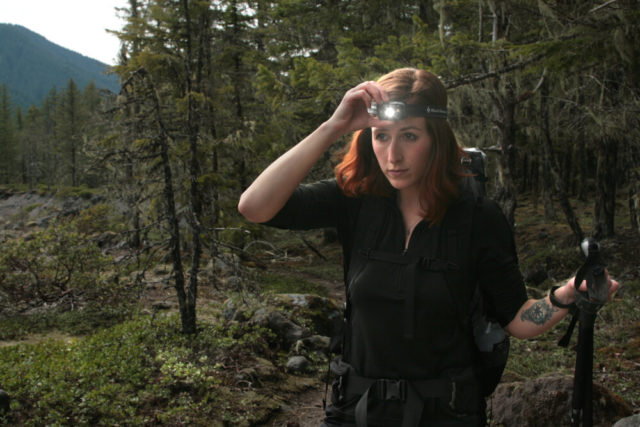 Red hair woman wearing headlamp while hiking in the woods
