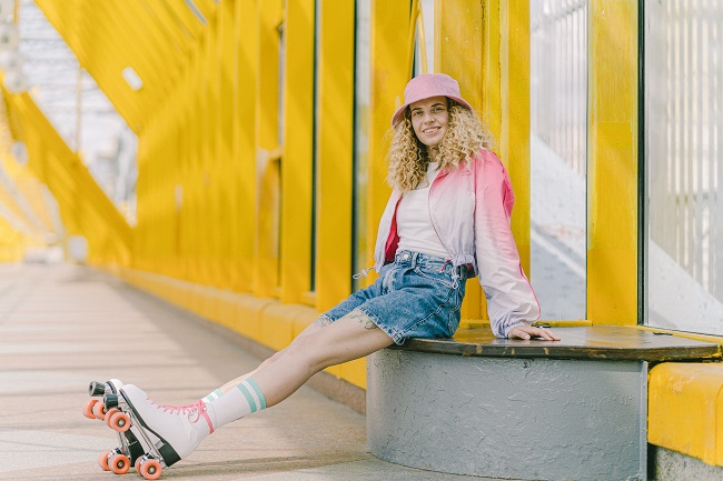 picture of a girl in roller skates sitting on a concrete bench beside a yello walls