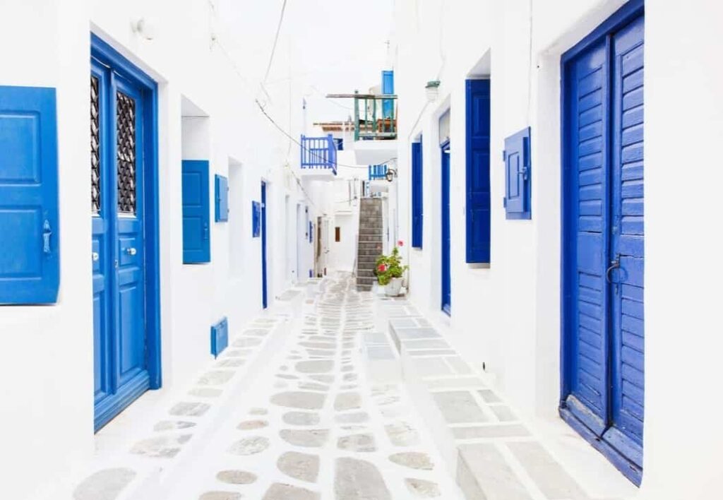 Greek Street in Mykonos with blue doors and white floor and walls