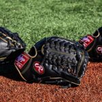three black softball mitts on a field