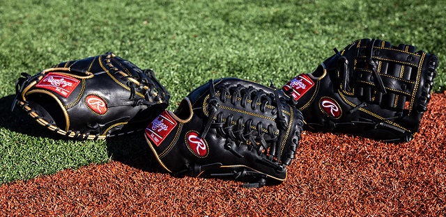 three black softball mitts on a field