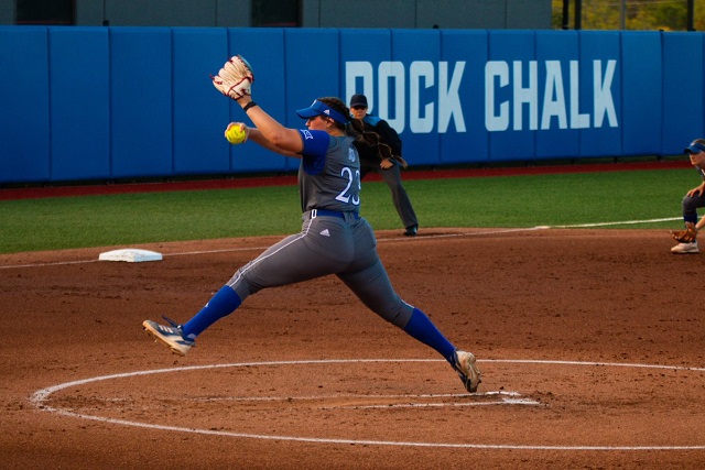 a softball player lunging forward to catch the ball