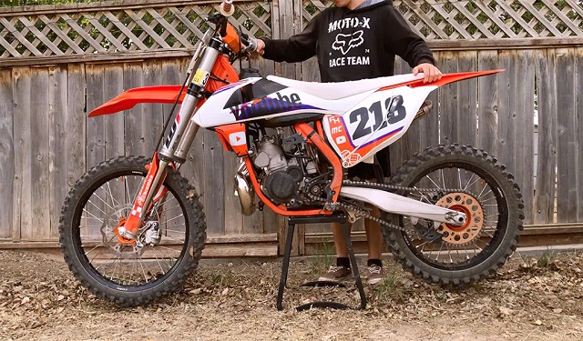 Man standing by dirt bike on stand